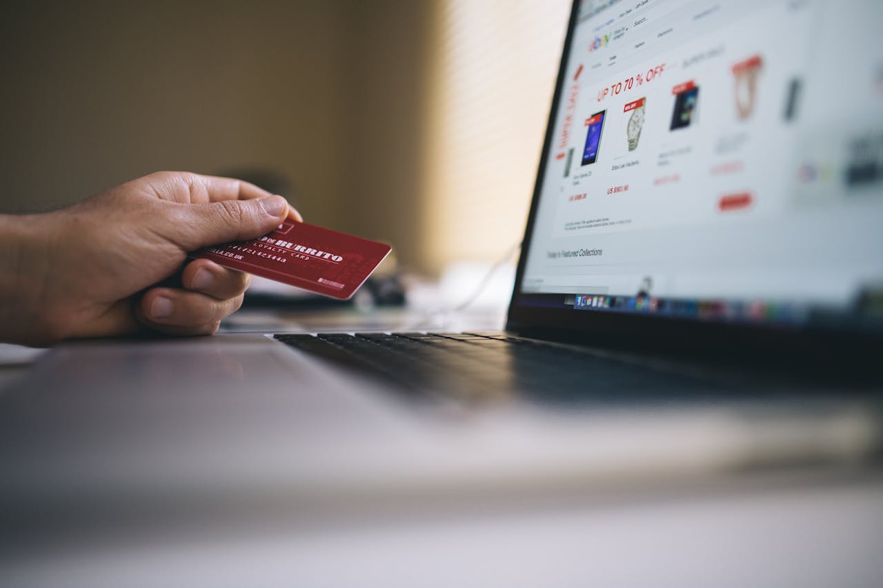 why-choose-us Person holding a credit card while shopping online on a laptop, indicating ecommerce transactions.